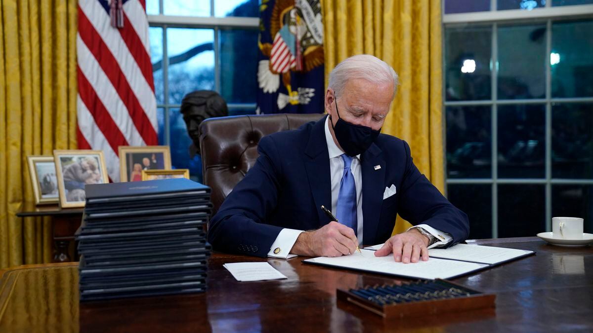 President Joe Biden signs his first executive order in the Oval Office of the White House on...