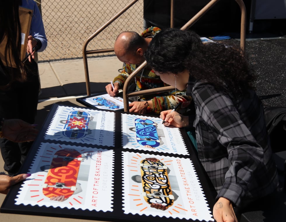 Artist Crystal Worl signing her design of a blue and indigo sockeye salmon for the USPS Art of...